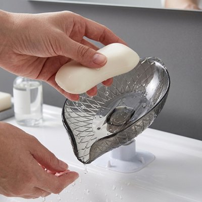 Porte savon ventouse transparent gris doté d'un système d'évacuation d'eau automatique et d'une base à ventouse.