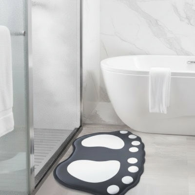 tapis salle de bain Forme de pieds stylisés avec motifs de galets bicolores.